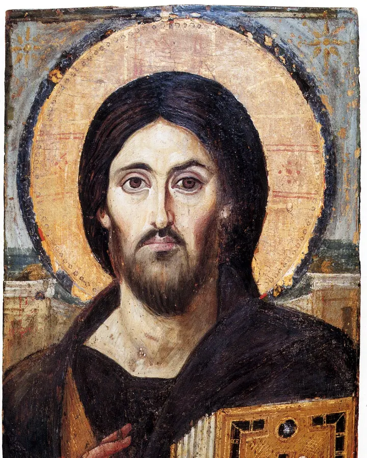 The Sinai icon of Christ Pantocrator. Christ holds a jewelled book of the Gospels in his left hand and blesses with his right, and the two sides of his face differ.